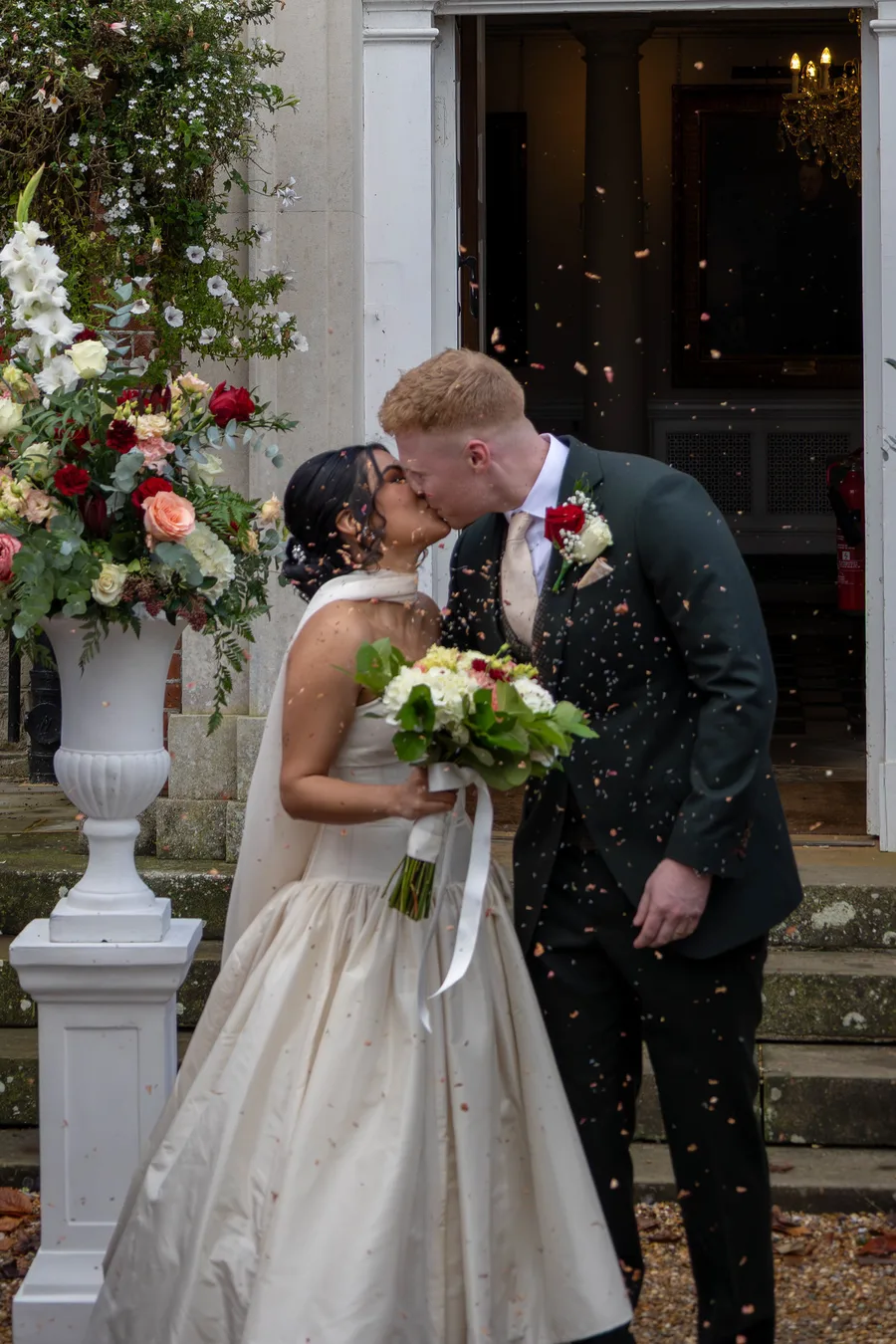 Confetti thrown as the couple kiss beside the ceremony flowers