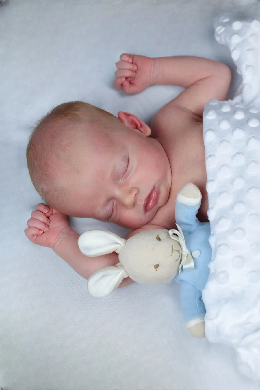 Newborn asleep beside a knitted bunny toy