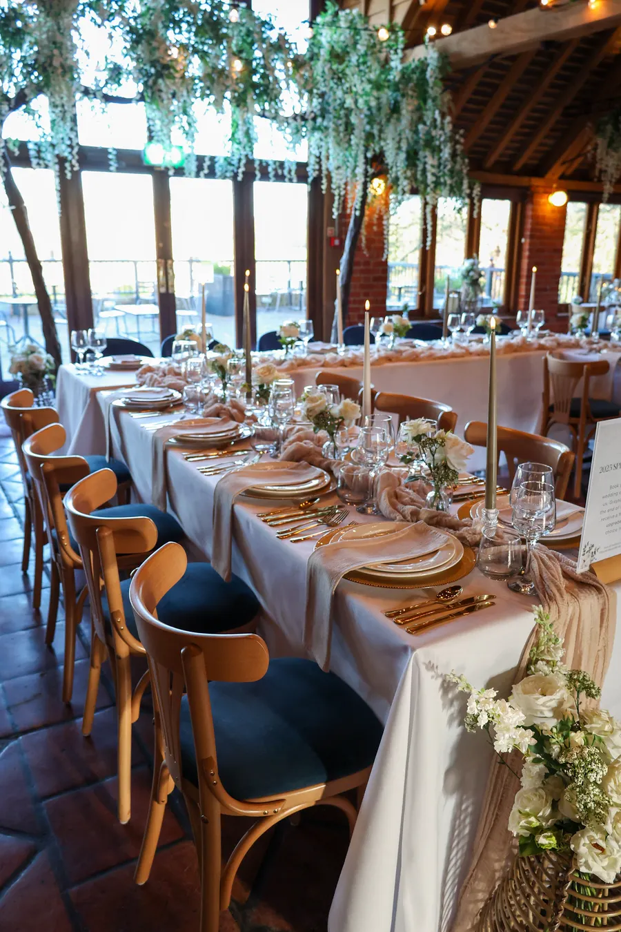 Table run with white linen, gold cutlery and trailing greenery
