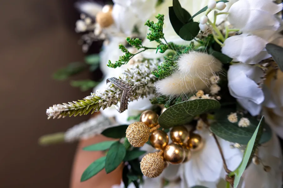 Close-up of a bridal bouquet of white roses, eucalyptus and gold baubles