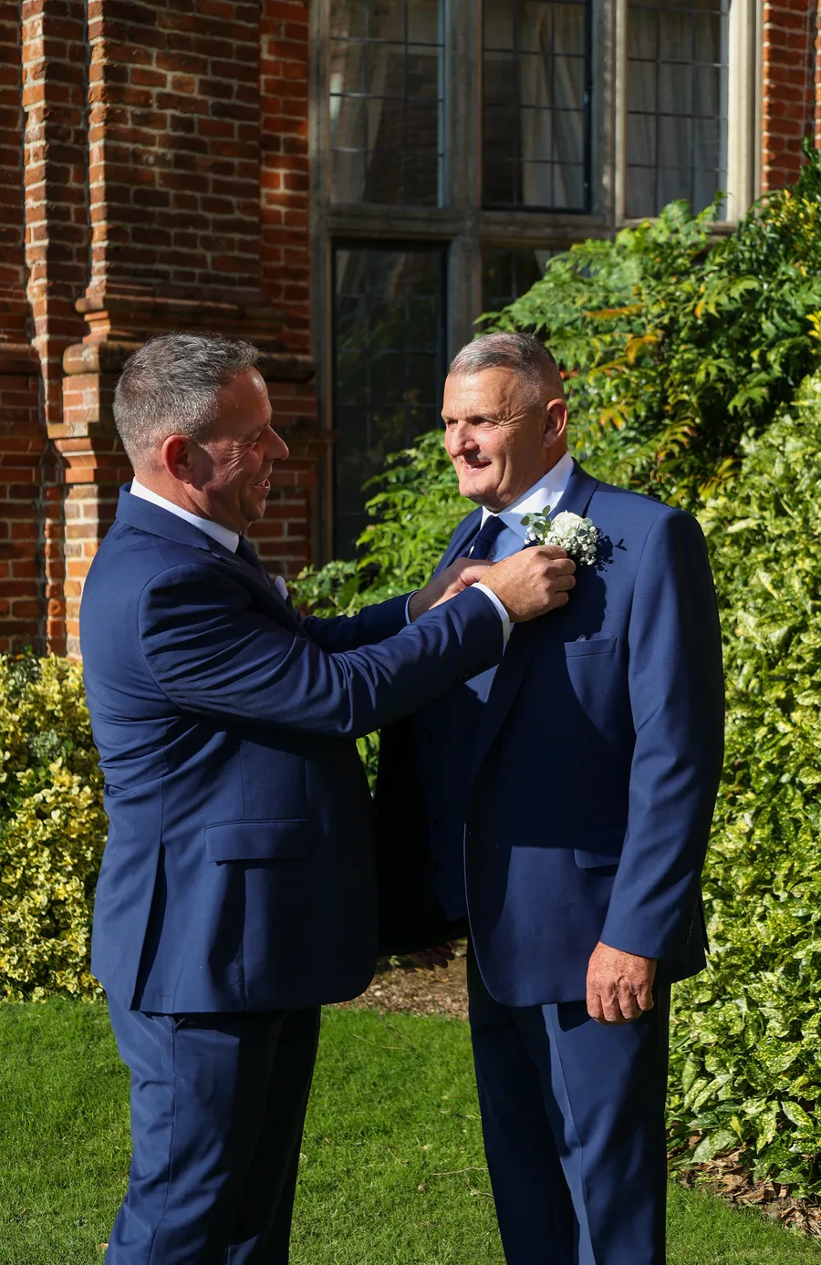 A best man’s final touch: Adjusting the groom’s boutonnière for a picture-perfect wedding moment.