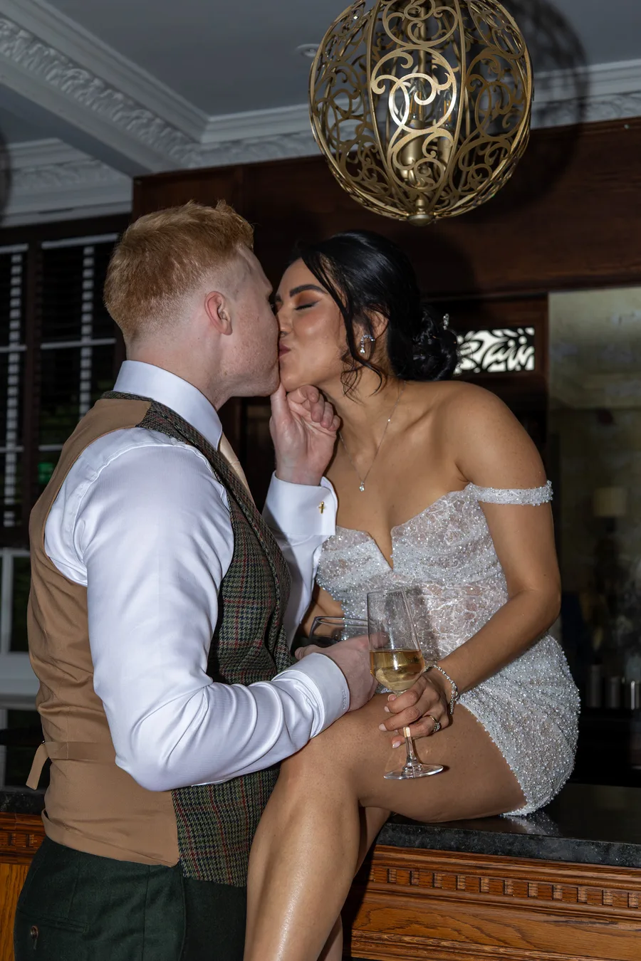Groom kissing the bride at the bar during the evening reception
