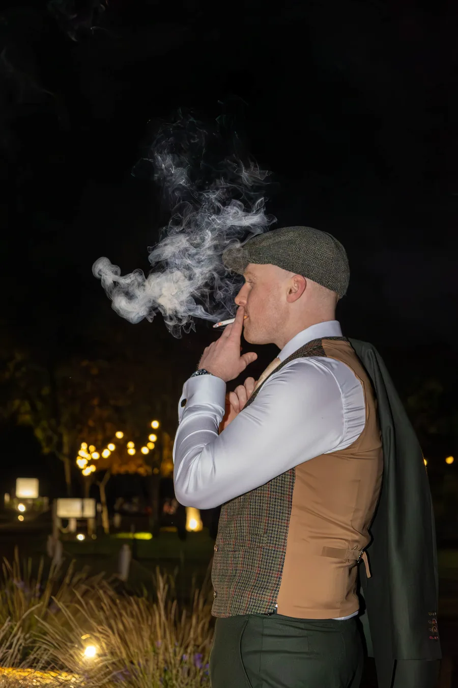 Groom smoking a cigar in the grounds at night
