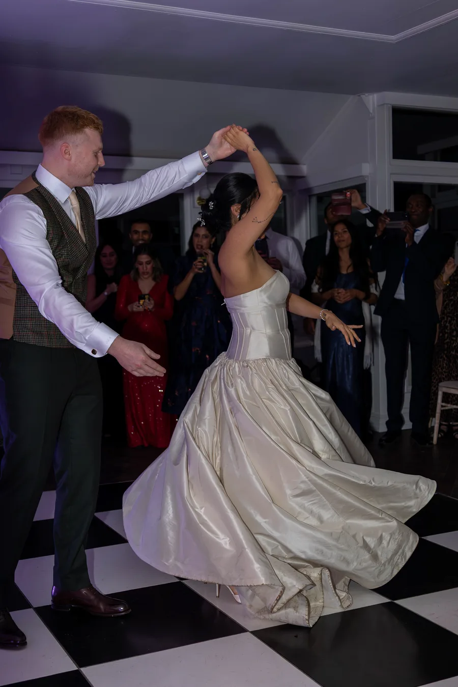 Groom spinning the bride on the chequered dance floor