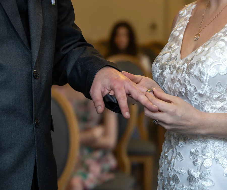 Groom sliding the ring onto the bride's finger during the ceremony