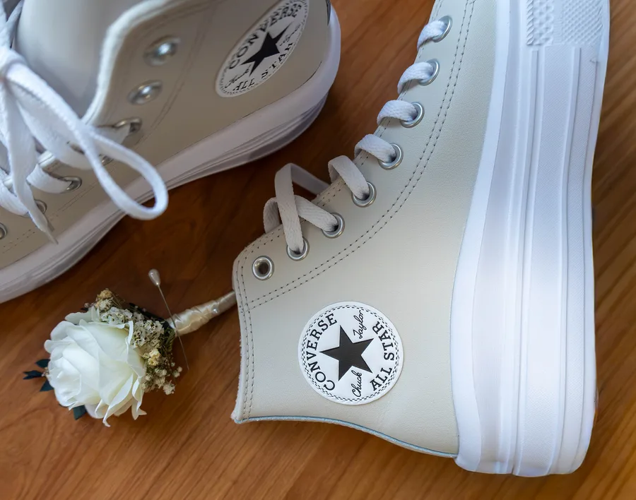 White Converse trainers and a buttonhole laid out on a wooden floor