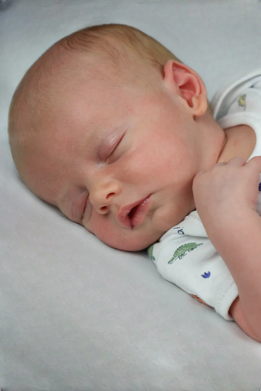 Newborn asleep in a dinosaur babygrow
