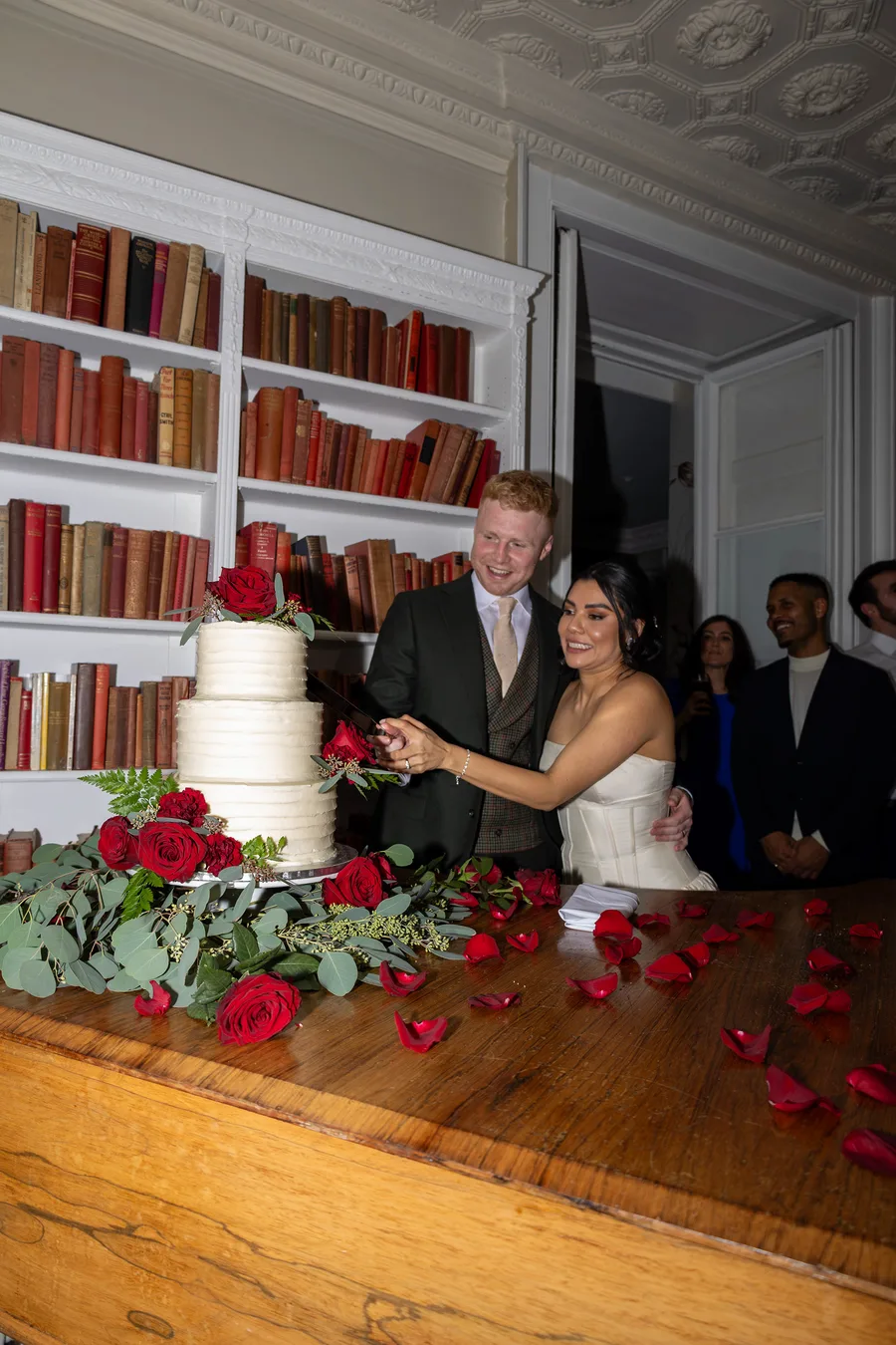 Bride and groom cutting their cake in the library