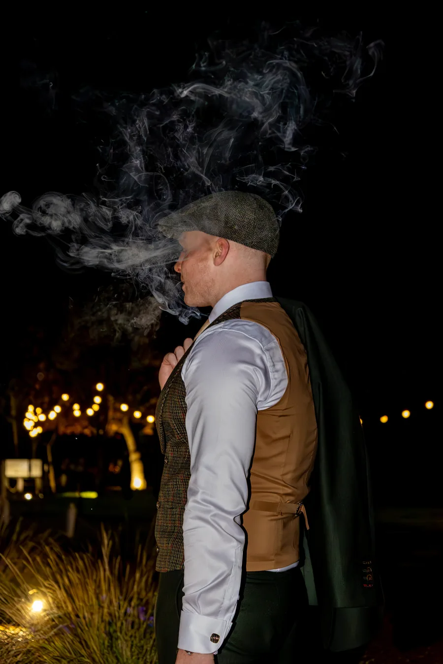 Groom smoking a cigar in the grounds at night