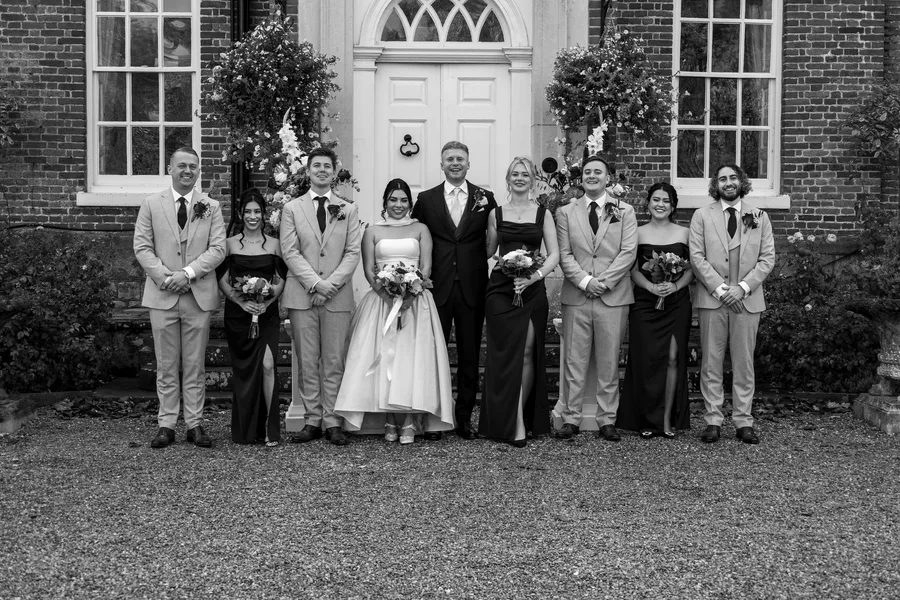 The full wedding party outside the house, in black and white