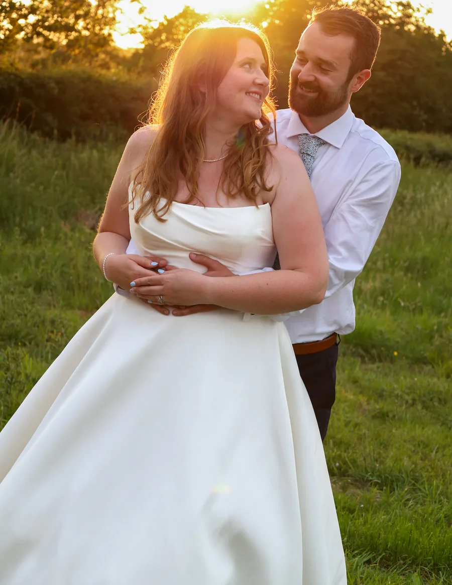 Groom holding the bride as the sun sets behind them