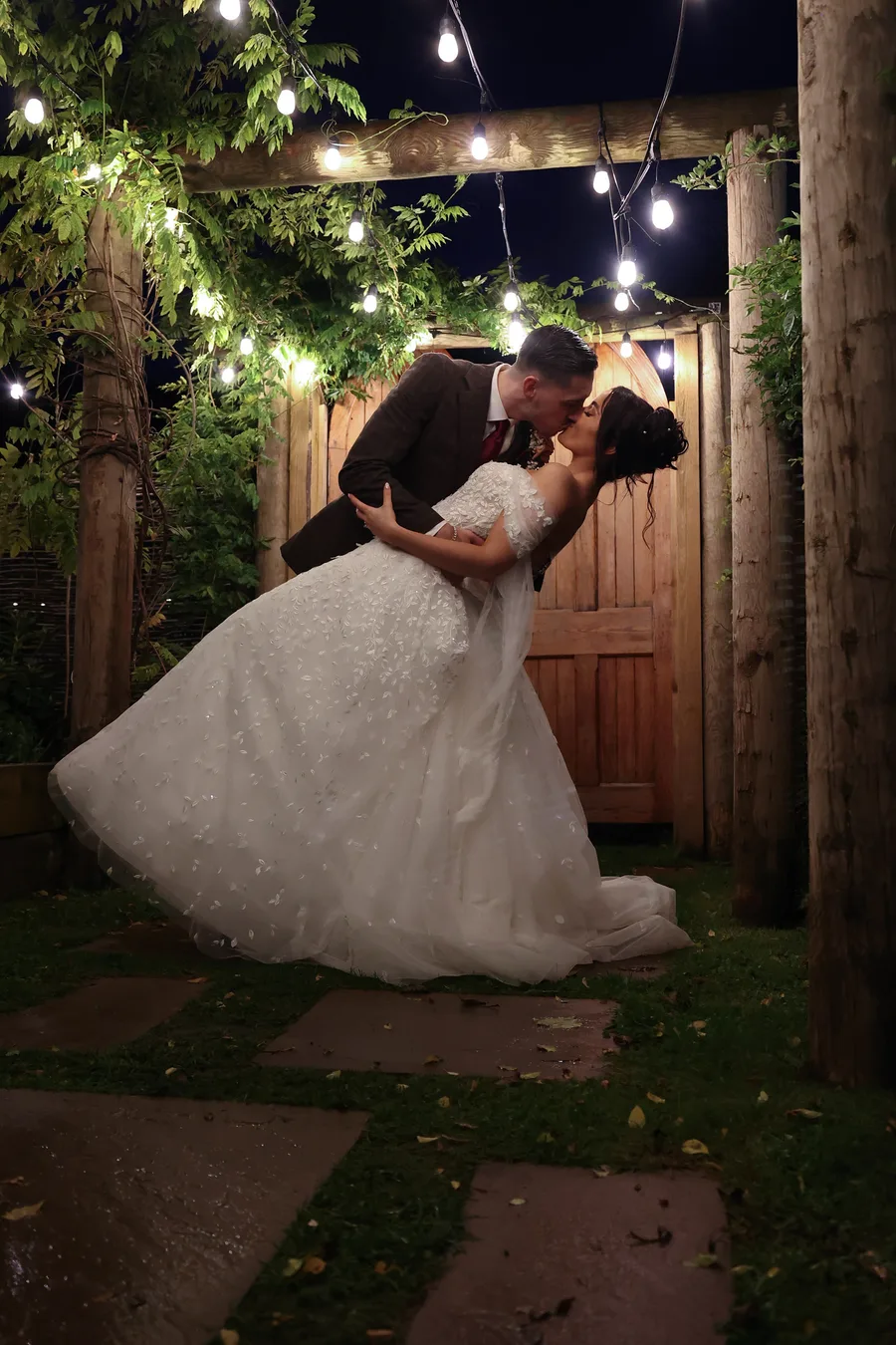 Groom dipping the bride for a kiss beneath the pergola