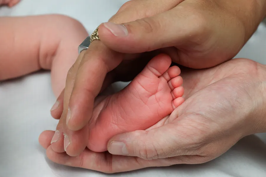 A newborn's feet held in adult hands