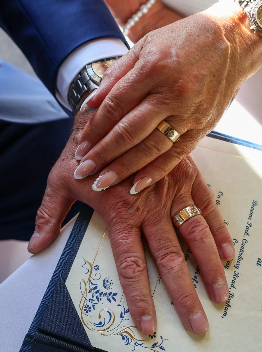 Hands resting on the marriage register, wedding rings showing