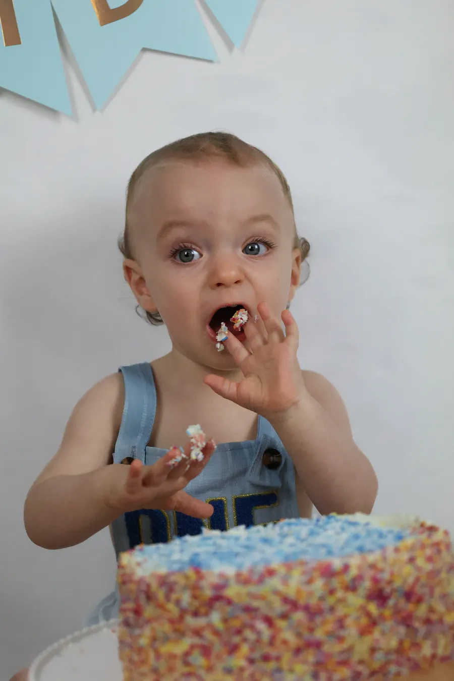Toddler tasting the icing at his cake smash session