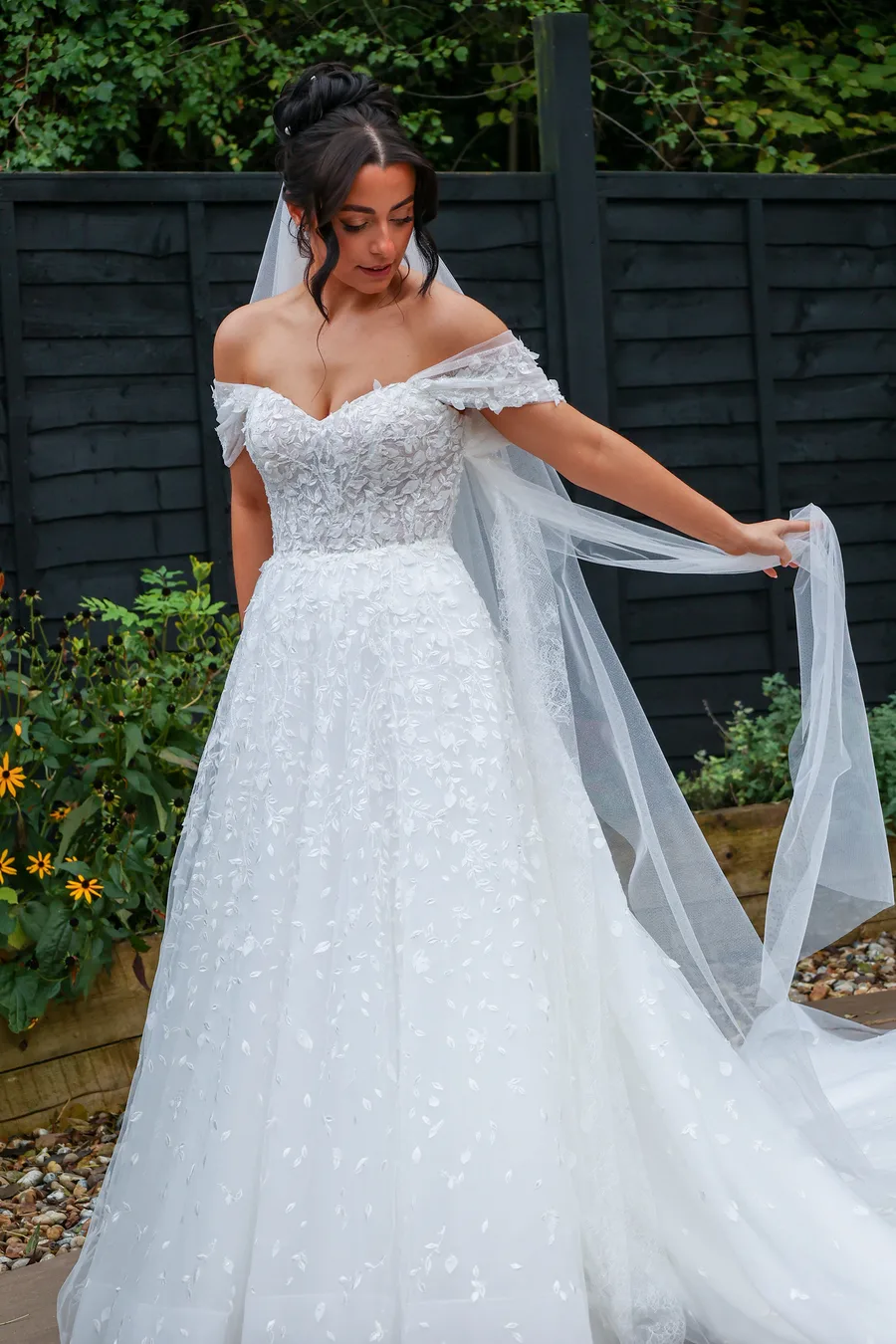 Bride holding out her veil in the garden