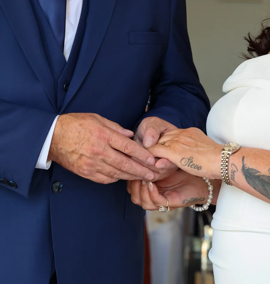 Close-up of the groom holding the bride's hands, their rings showing