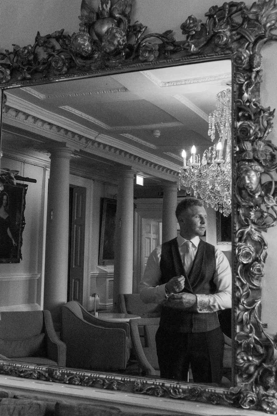 Groom reflected in an ornate gilt mirror, in black and white