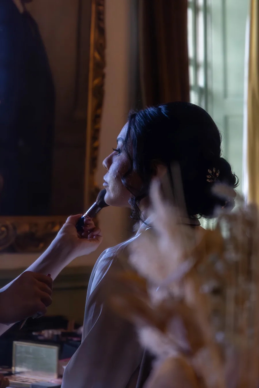 Bride having her make-up done beside a window