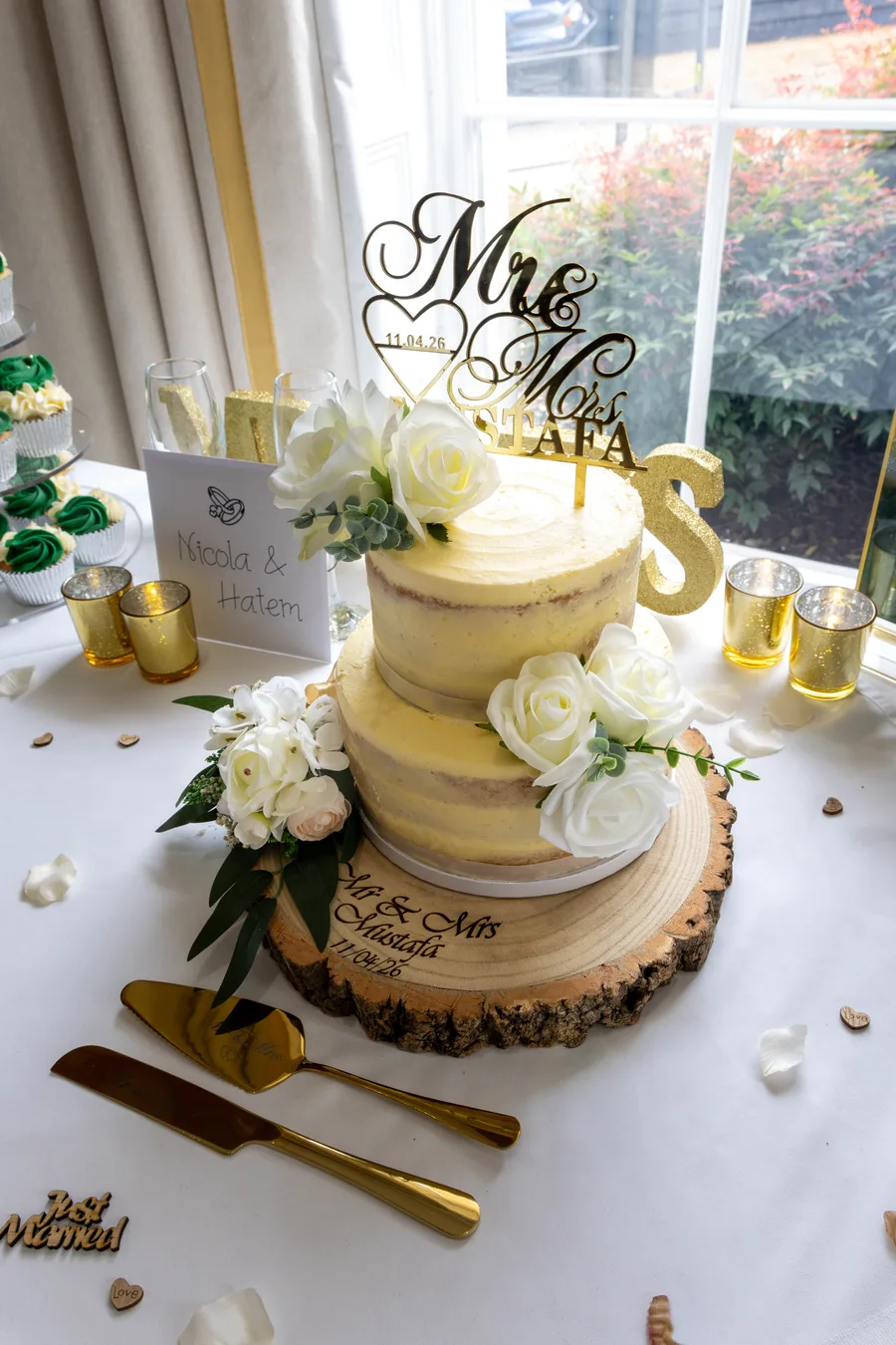 Two-tier wedding cake with white roses and a gold Mr and Mrs topper