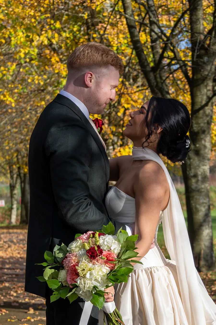 Bride and groom together among the autumn leaves