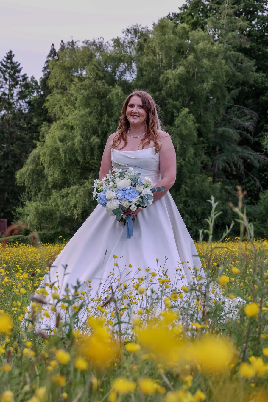 Bride holding her bouquet in a buttercup meadow at golden hour