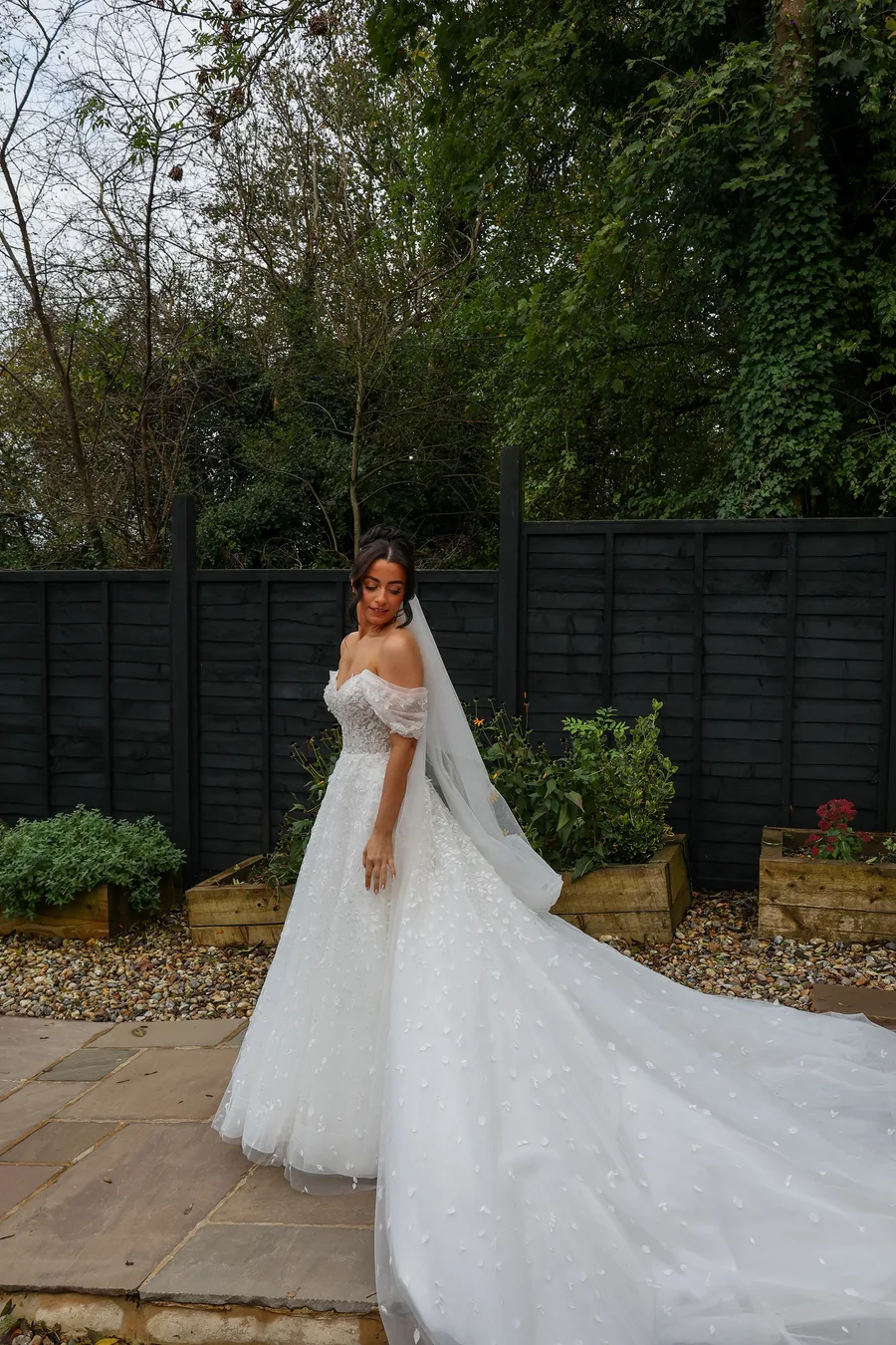 Bride with her long train on the garden path at dusk
