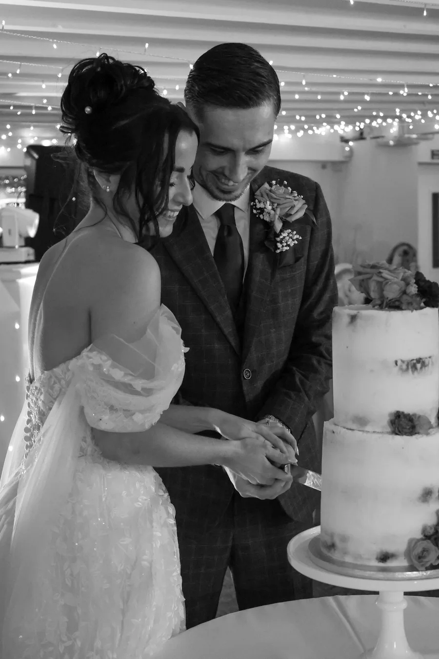 Bride and groom cutting their wedding cake, in black and white