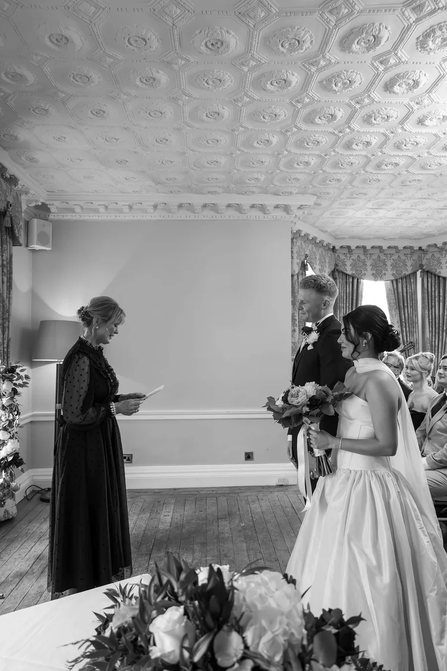The registrar conducting the ceremony as the couple listen, in black and white