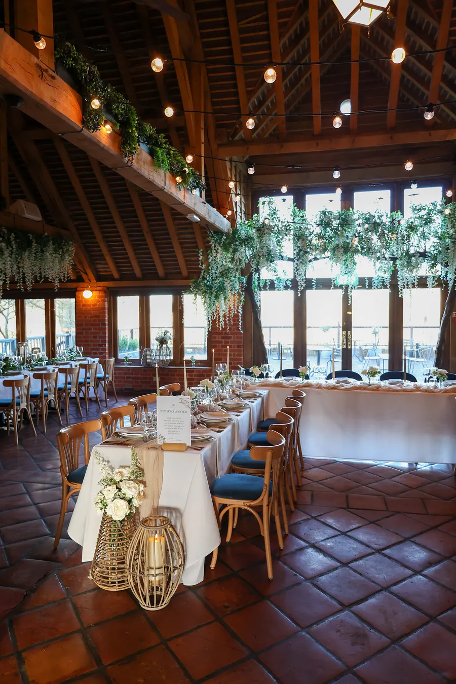 A beamed barn dressed for a party with fairy lights and lanterns