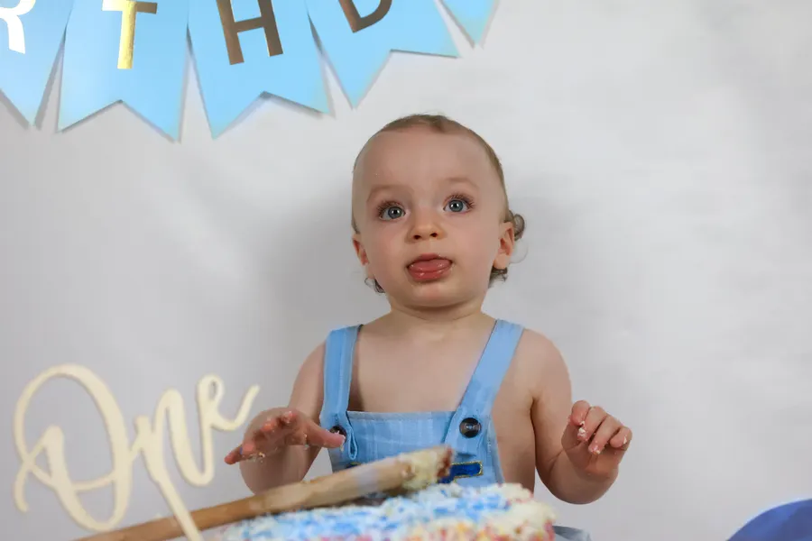 Toddler with his birthday cake and a gold One sign
