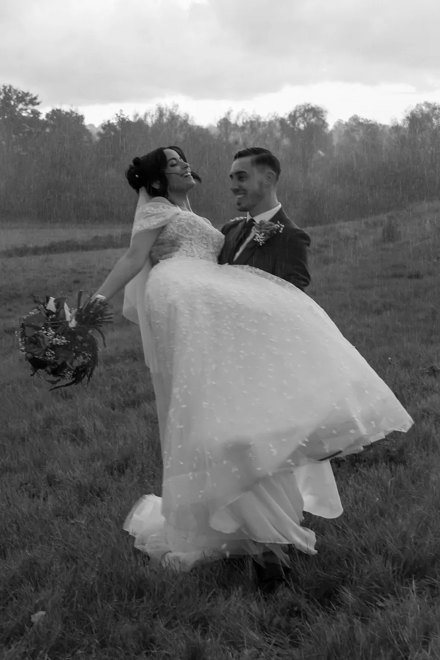 Groom lifting the bride in a field, in black and white