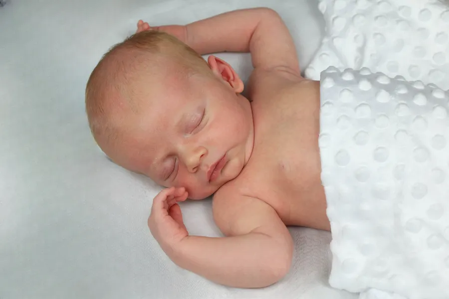 Newborn asleep on a dimpled white blanket