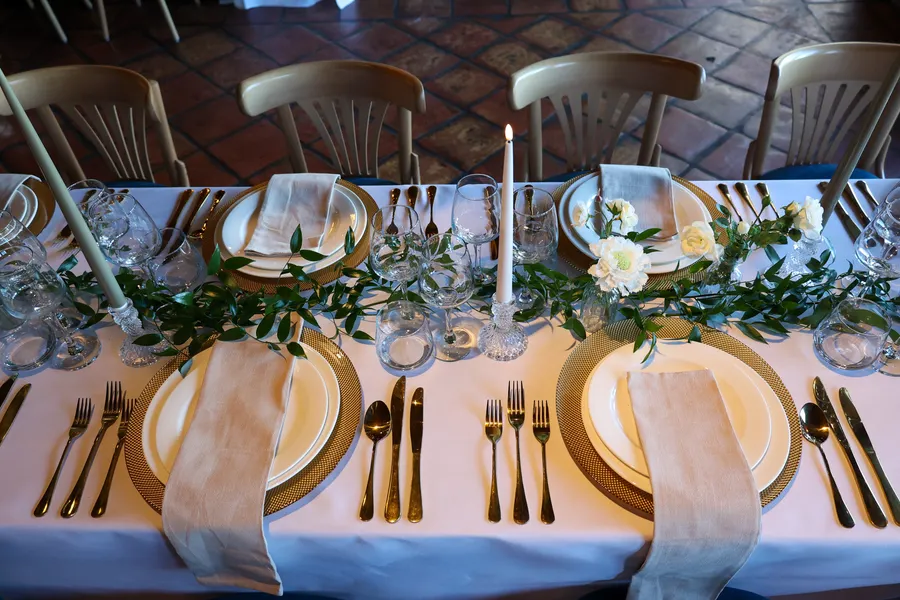Close-up of a place setting with candles and eucalyptus along the table