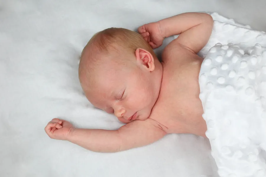 Newborn sleeping with both arms stretched out
