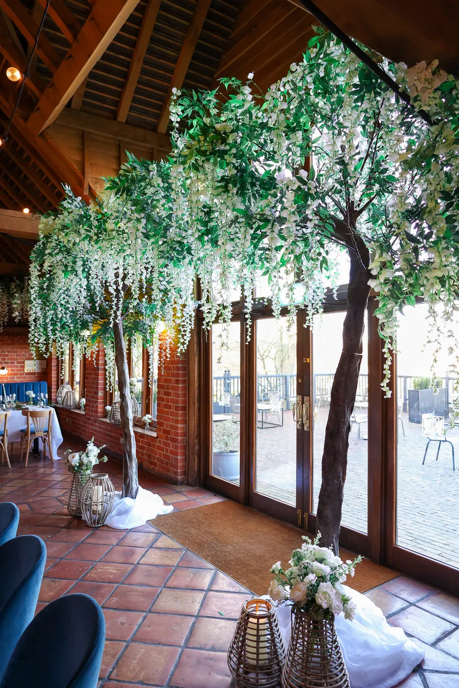Blossom trees and greenery framing the entrance of a barn venue