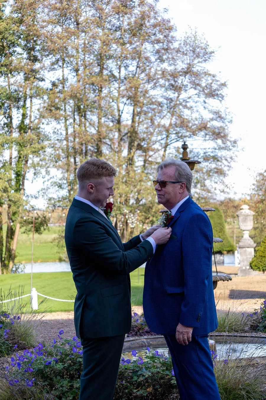 Groom having his buttonhole fixed in the gardens